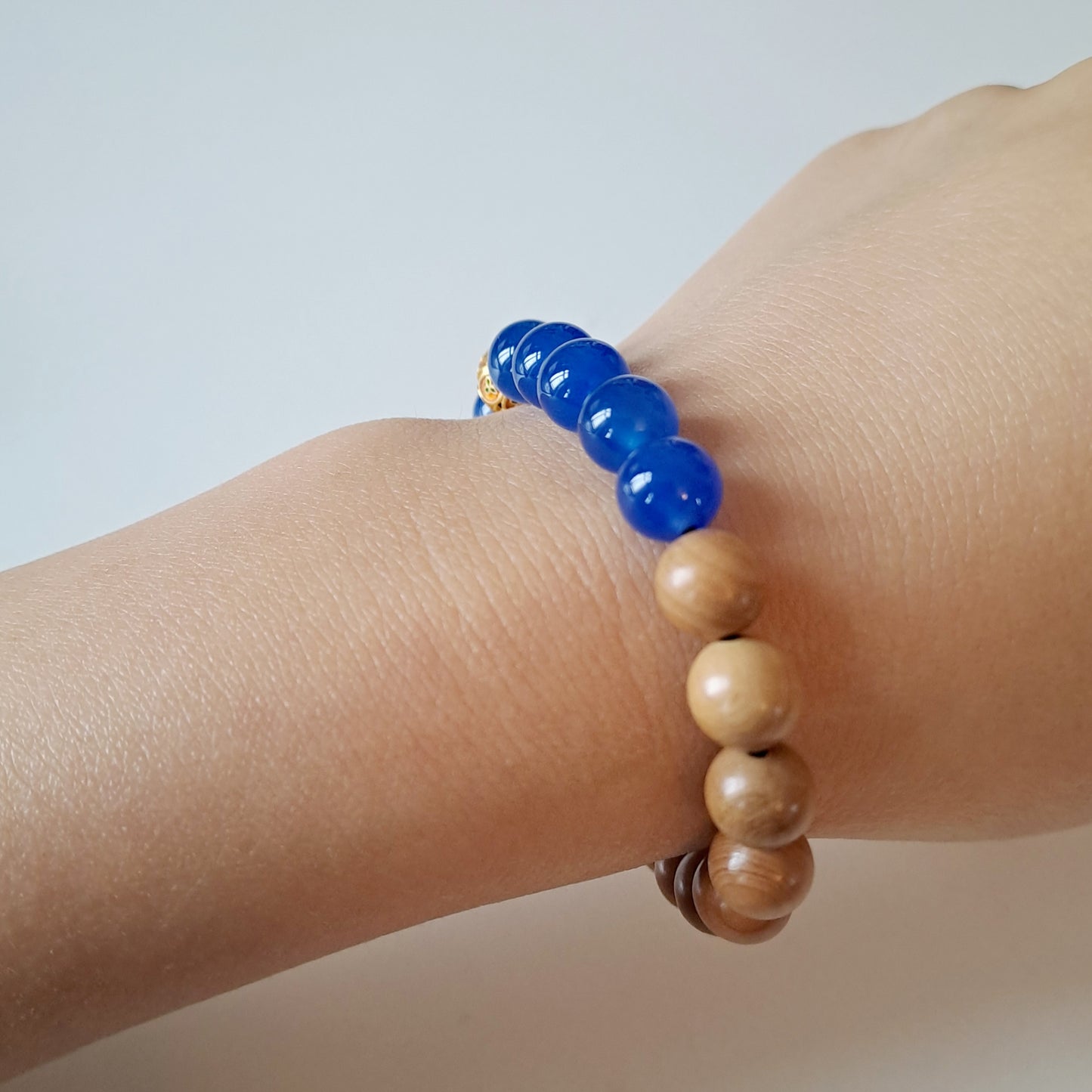 Natural sandalwood beads paired with blue agate beads and Tibetan silver fortune beads bring good luck and assist in meditation