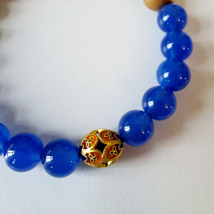 Natural sandalwood beads paired with blue agate beads and Tibetan silver fortune beads bring good luck and assist in meditation